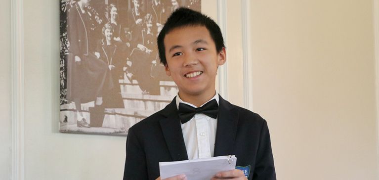 A young Chase Collegiate student in a tuxedo gives a speech.